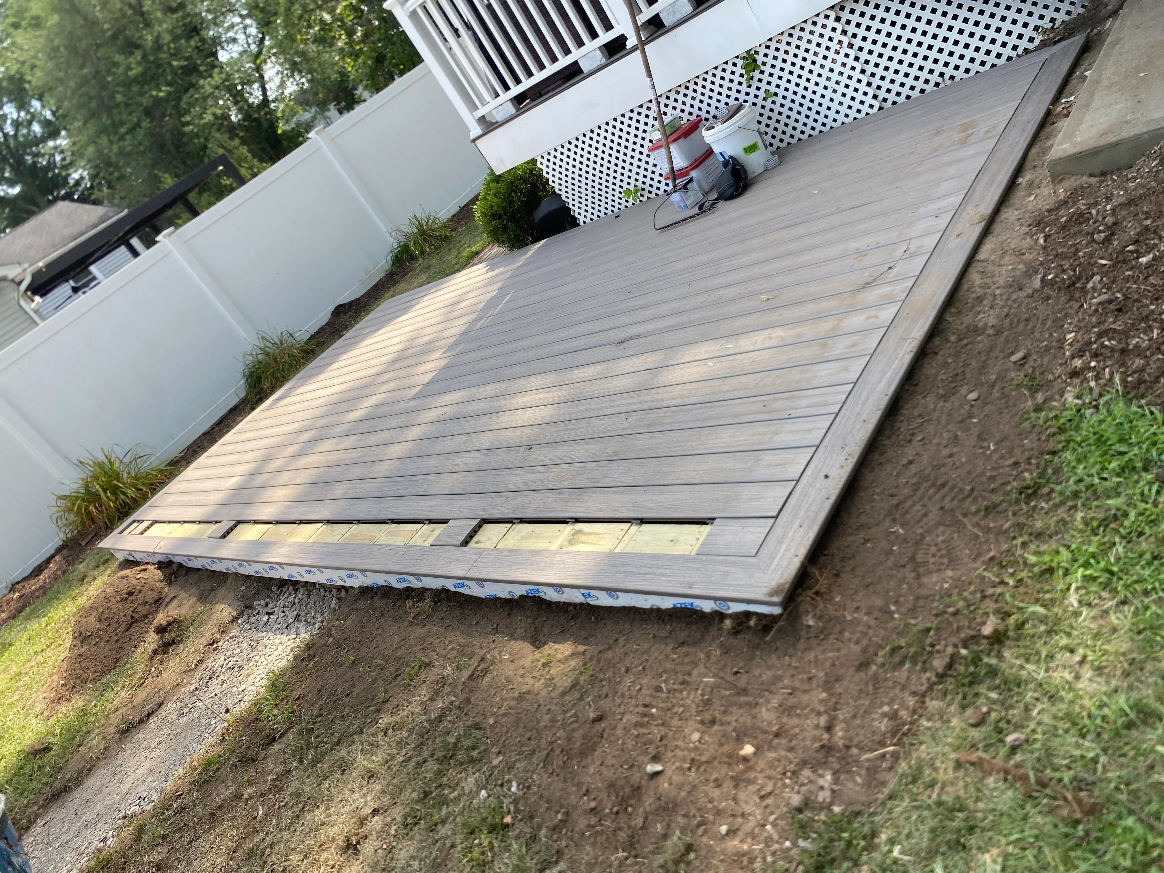Gray composite deck boards installed over moisture barrier on prepared ground base