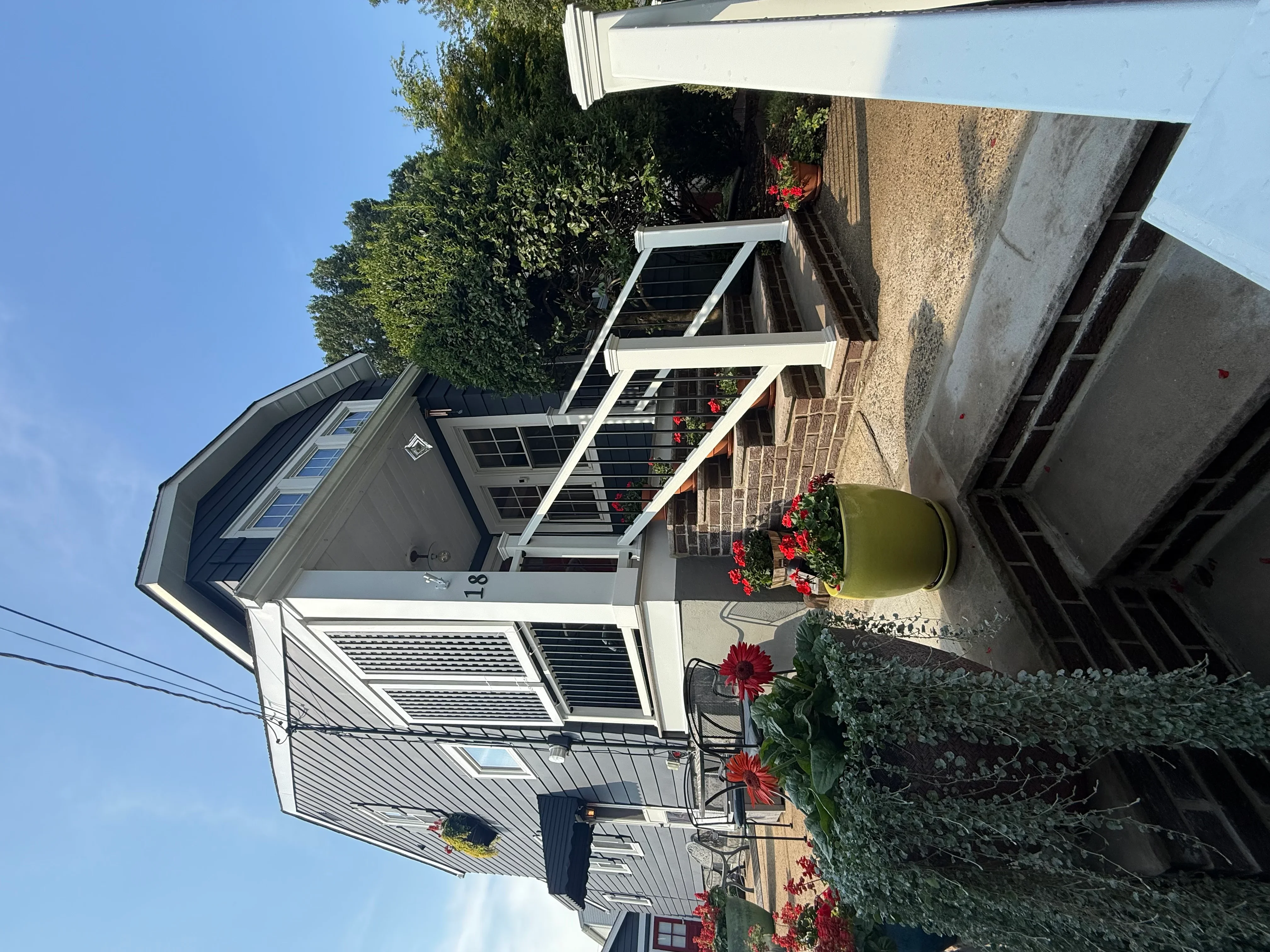 White-trimmed entryway with horizontal siding, new windows, and flowering planters