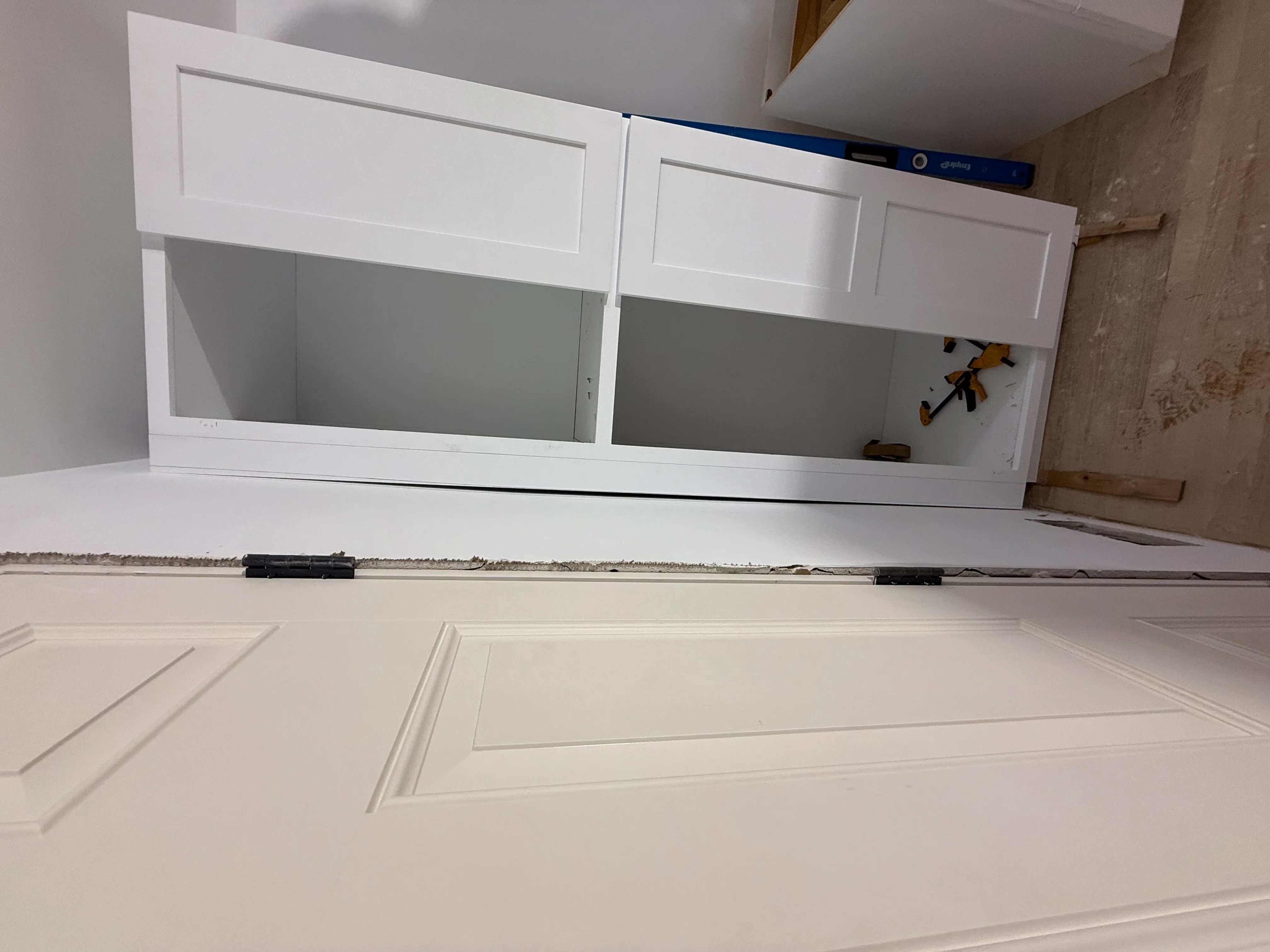 White shaker kitchen cabinets with recessed panel doors during installation phase