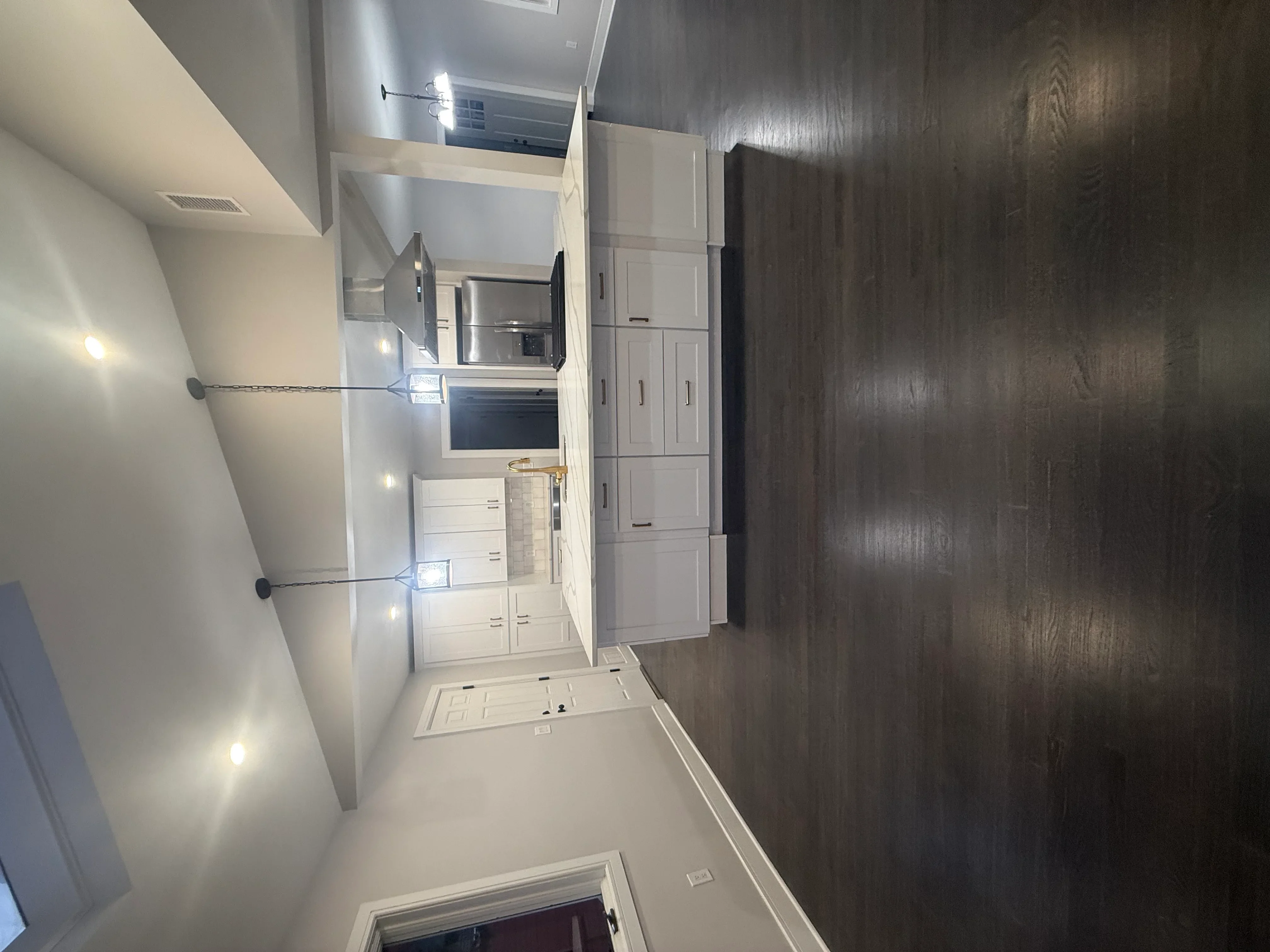 White kitchen cabinets with stainless steel appliances and recessed lighting
