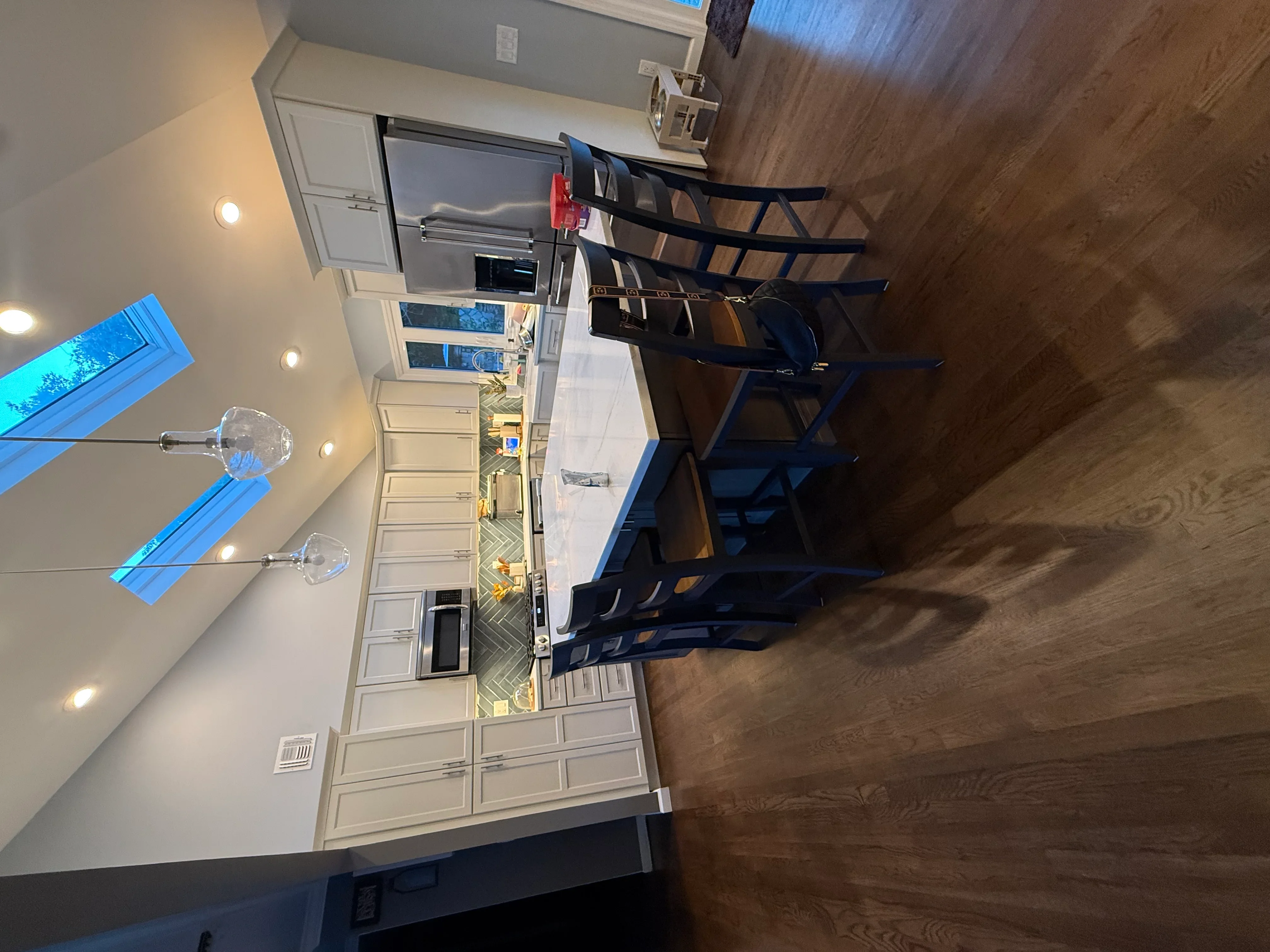 Kitchen with white cabinetry, hardwood floors, recessed lighting, and black bar seating