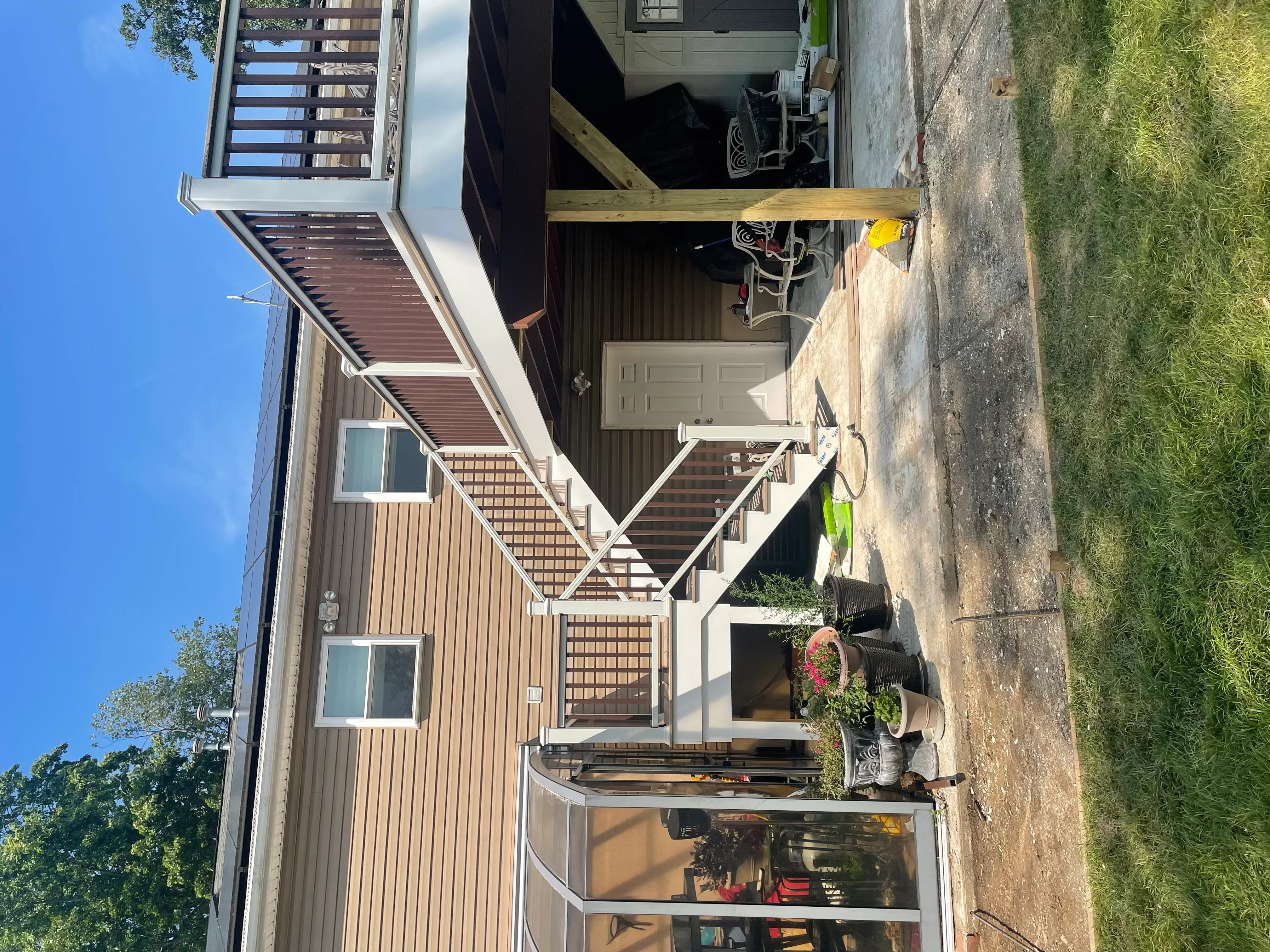 New composite deck with white railings, metal siding, brick accents, and updated entry stairs on residential home