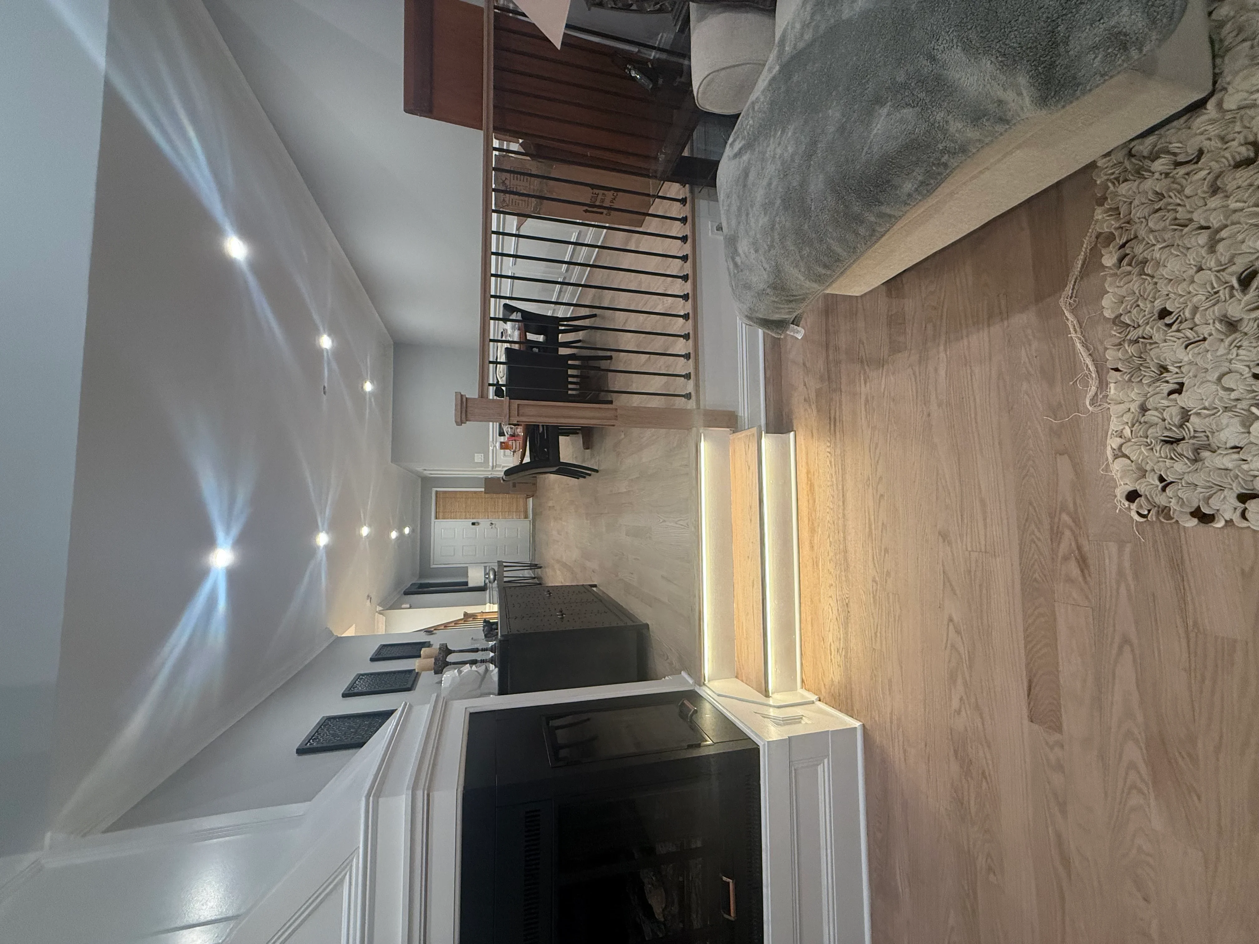 Modern kitchen with white cabinetry, wood flooring, black range, and recessed lighting