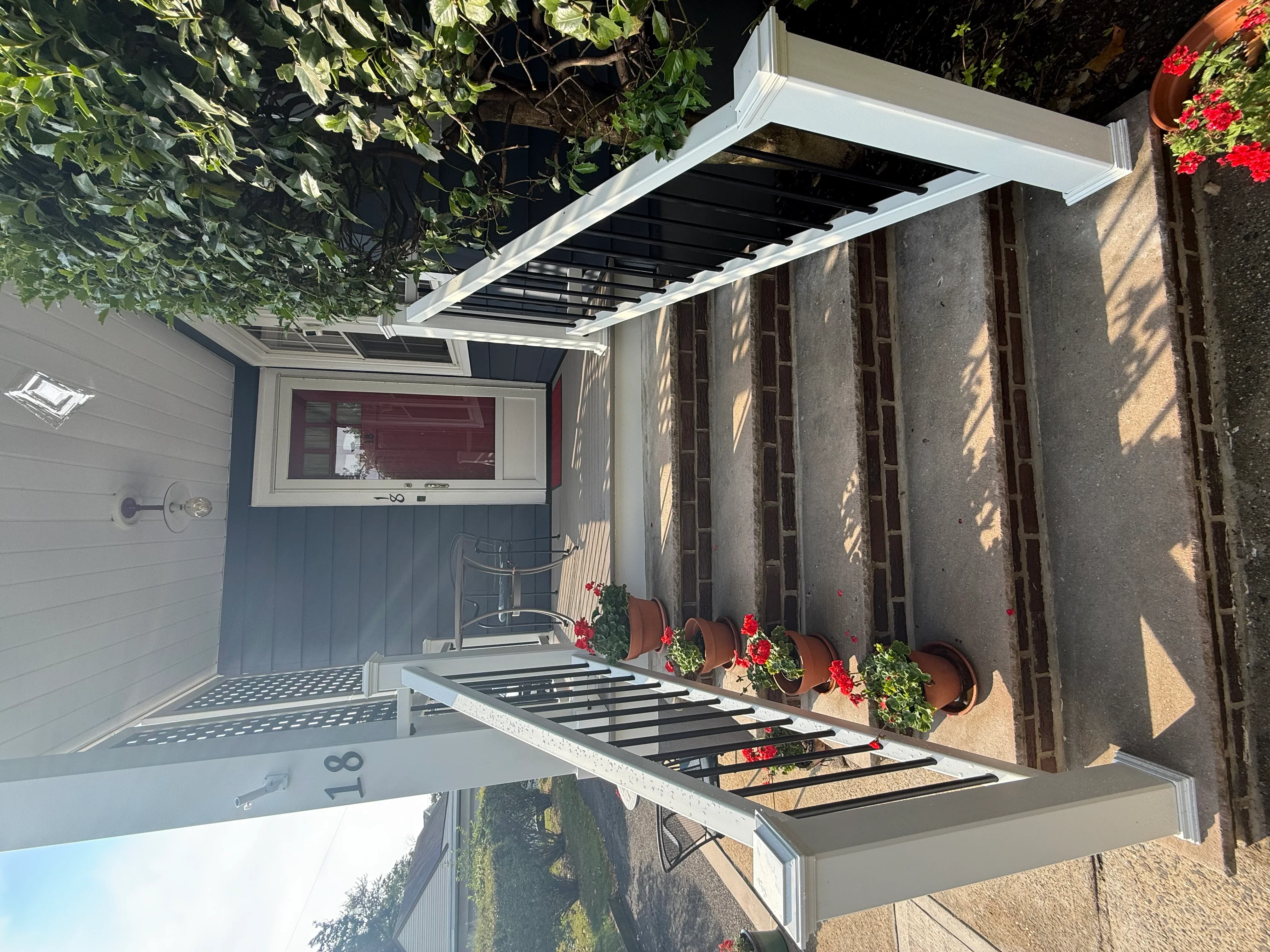 White aluminum pergola with black louver slats over outdoor kitchen patio area