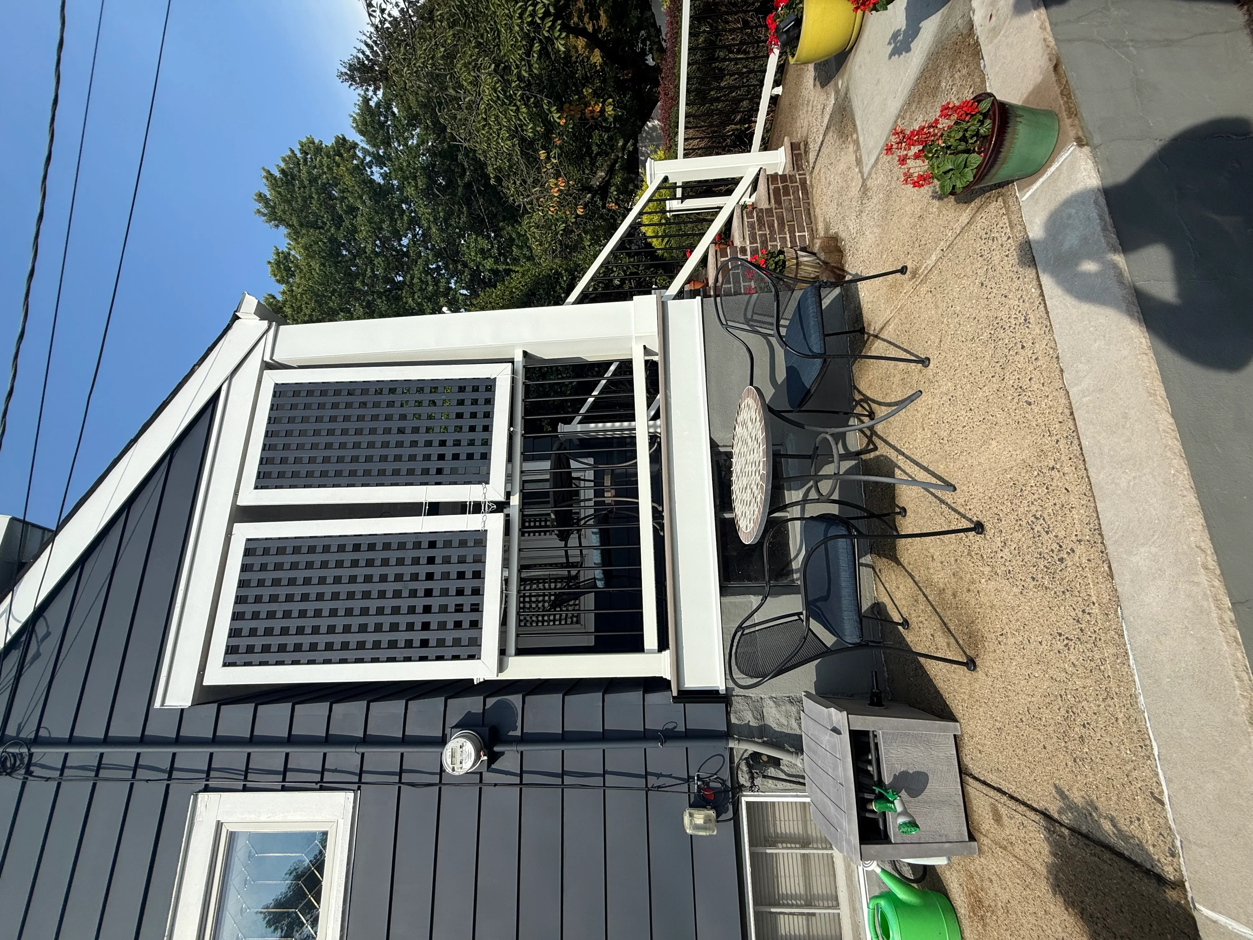 White double-hung windows with screens installed on residential exterior wall with stone patio