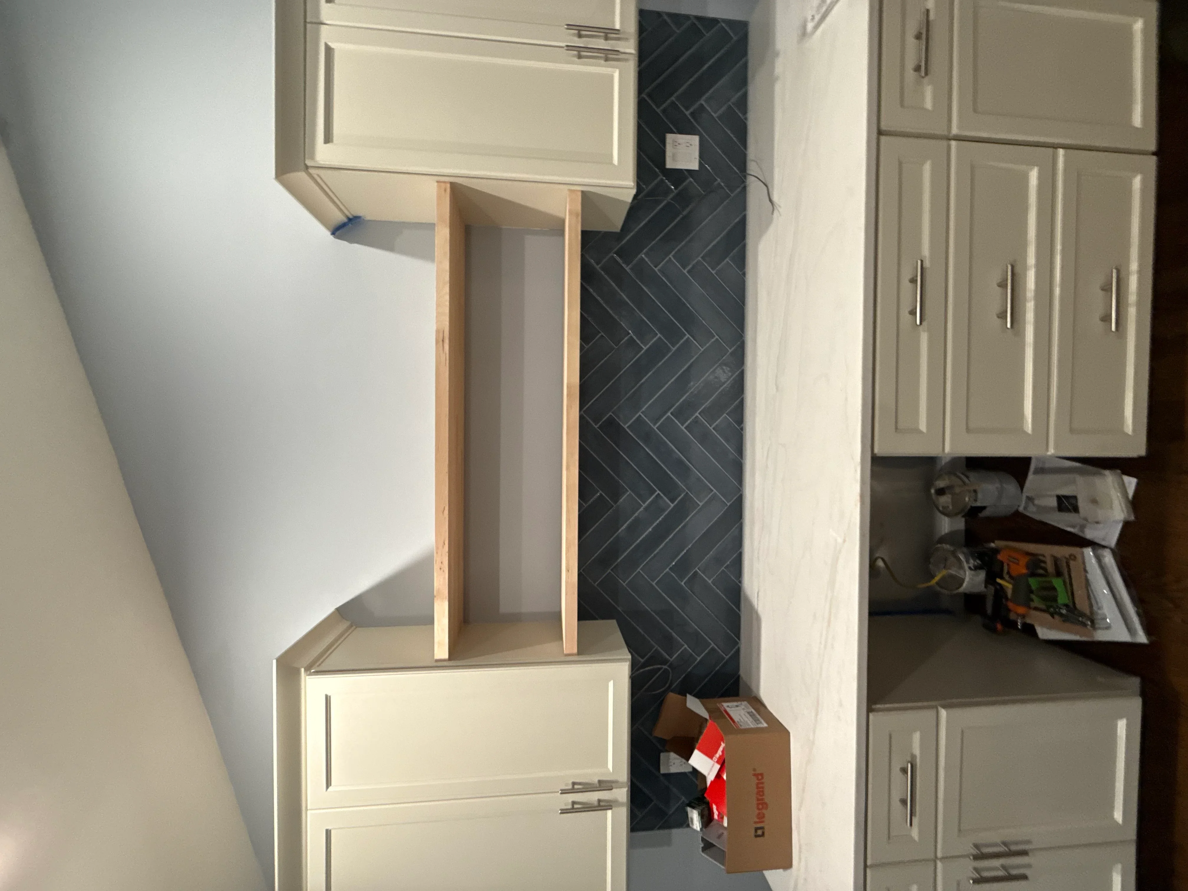 Cream kitchen cabinets with black herringbone tile backsplash and open shelving