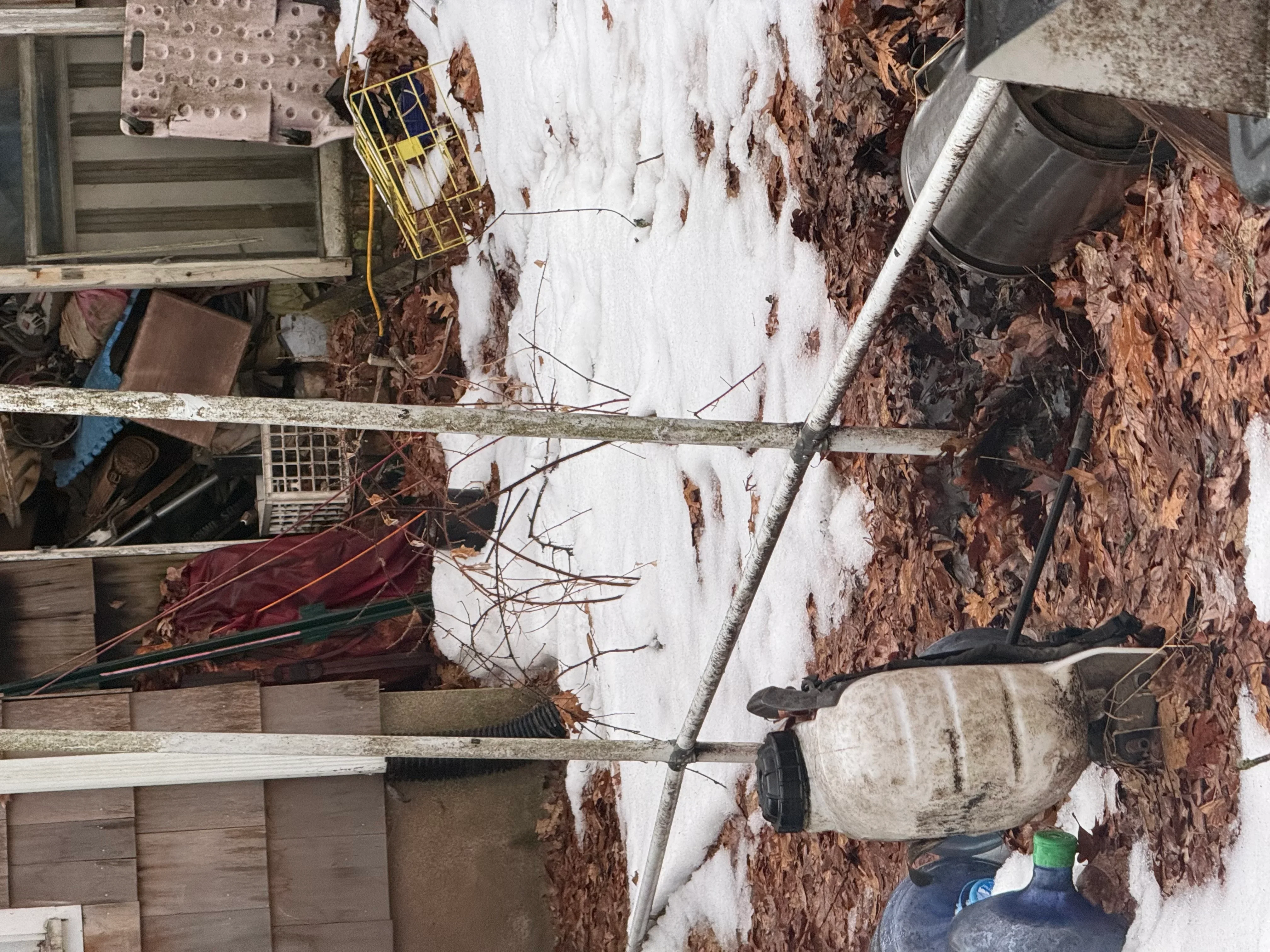 Exterior demolition with exposed wood framing, removed siding materials, and debris staging